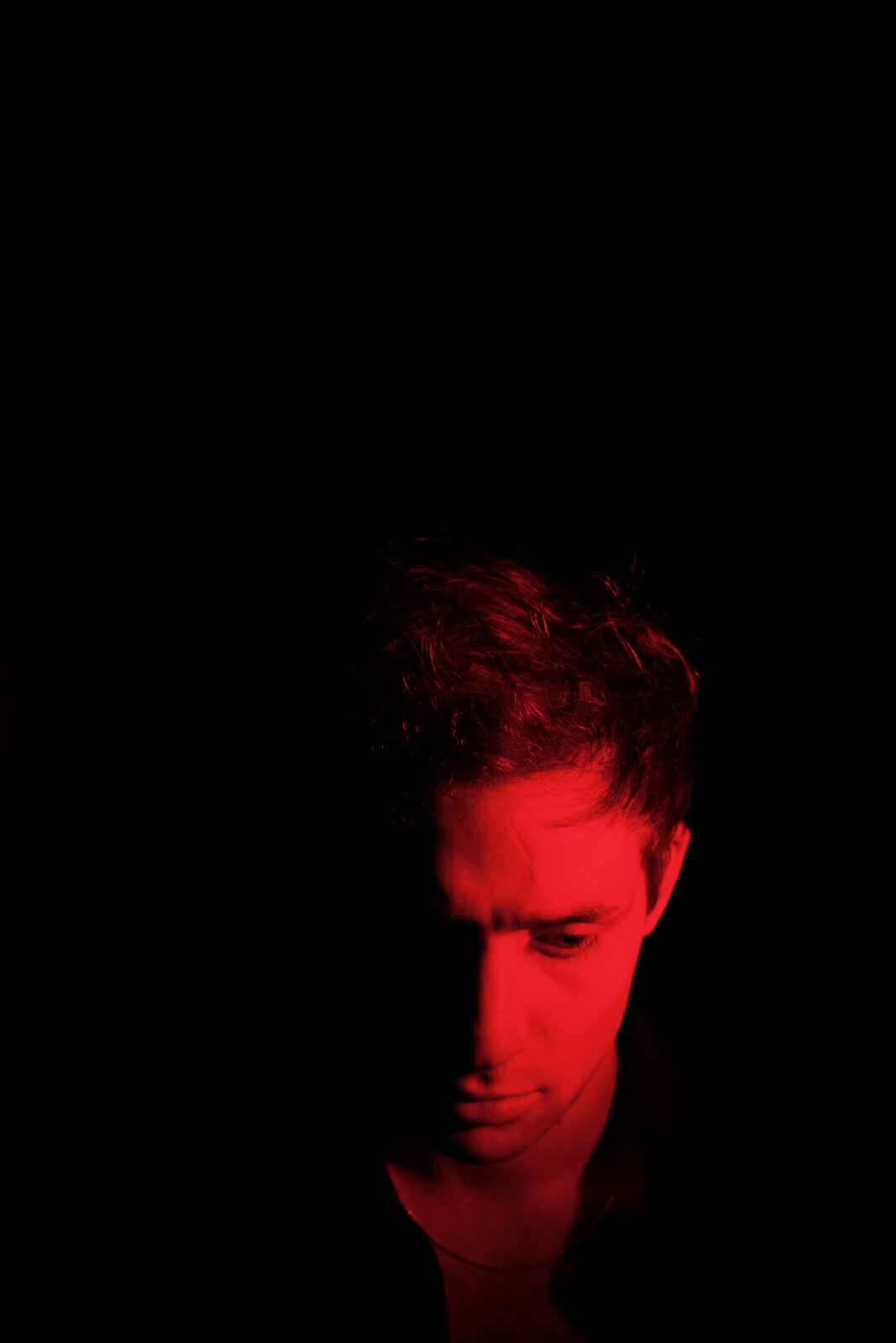 Sapphire Adizes portrait, head bowed in red light
